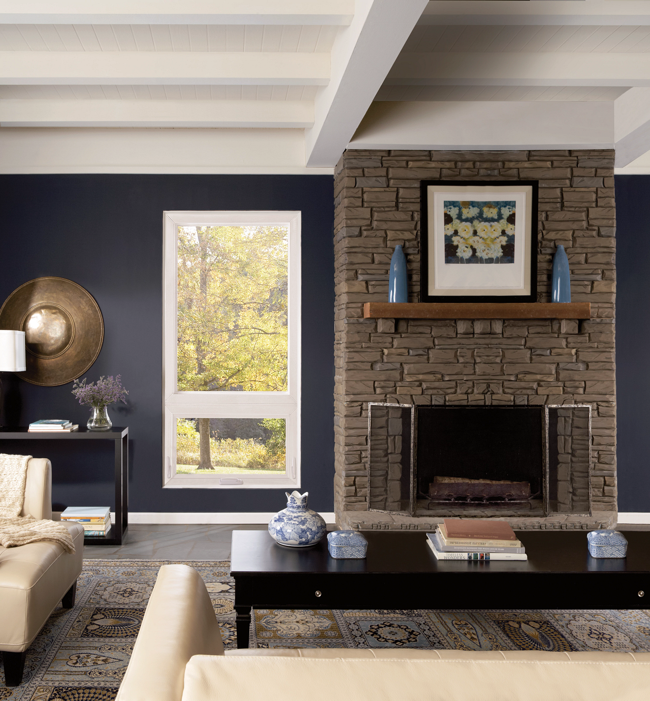 Modern living room with stone fireplace, navy wall, and light wood ceiling beams