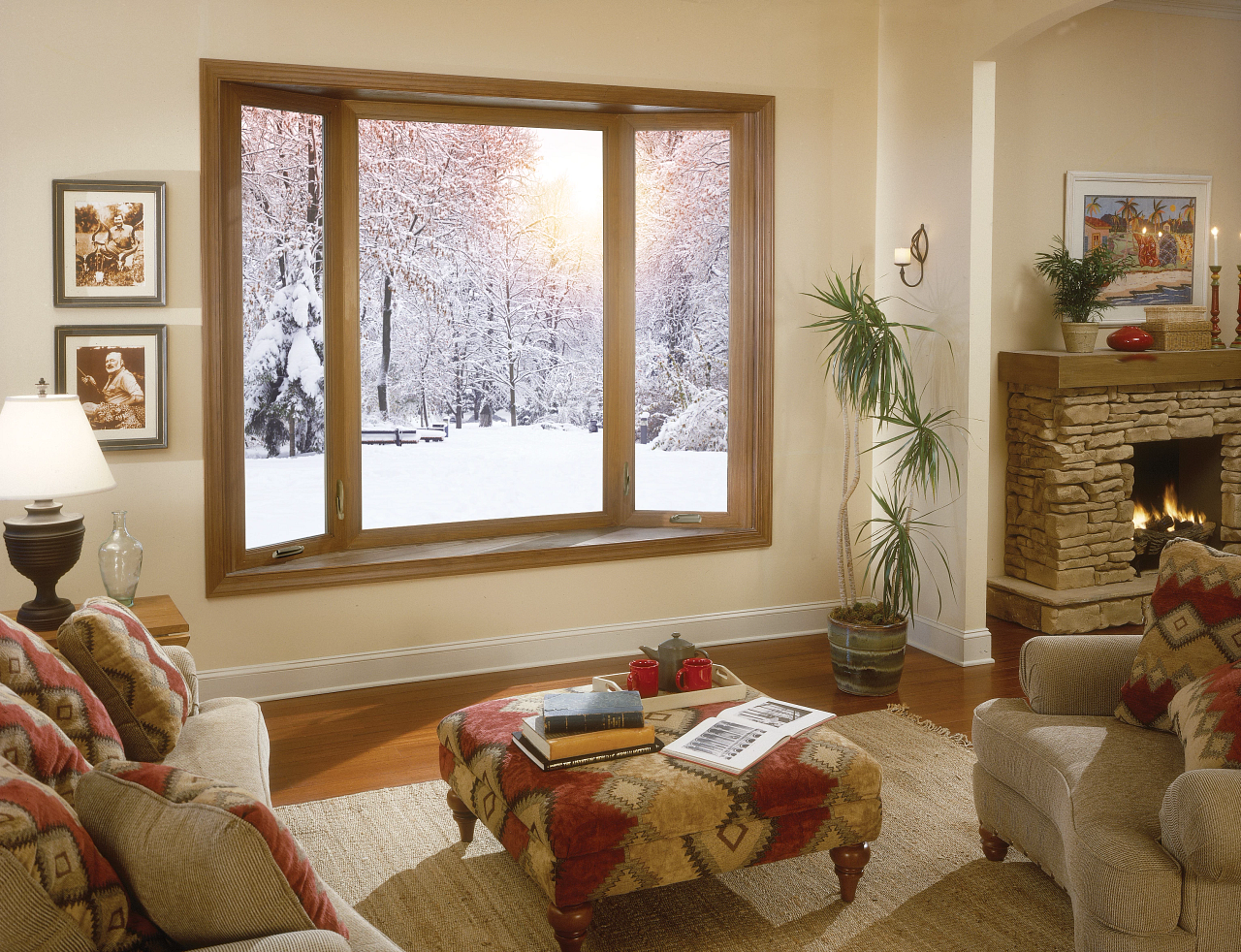 Cozy living room with sofas, fireplace, and large window overlooking a snowy forest