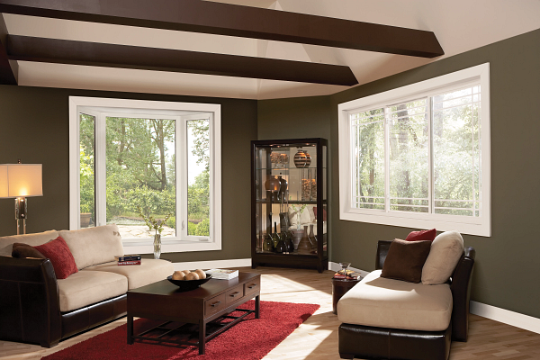 Bright living room with large windows, beige sofas, red rug, and dark ceiling beams.