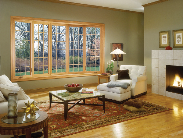 Cozy living room with large windows, fireplace, white chairs, and a patterned rug