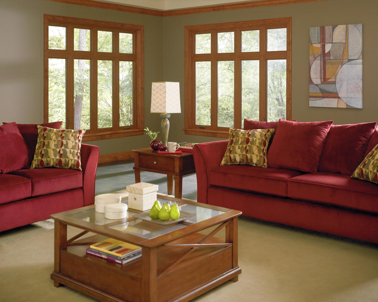 Modern living room with red sofas, wooden coffee table, and large windows with daylight.