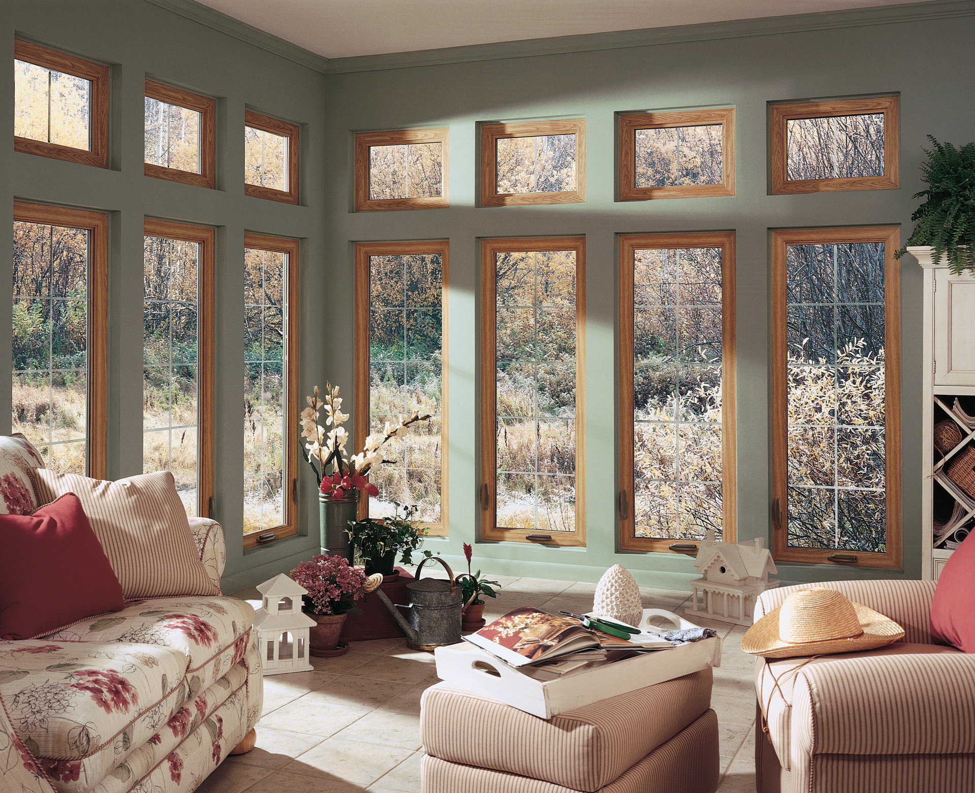 Cozy sunroom with large windows, floral sofa, and a central coffee table by a snowy garden view