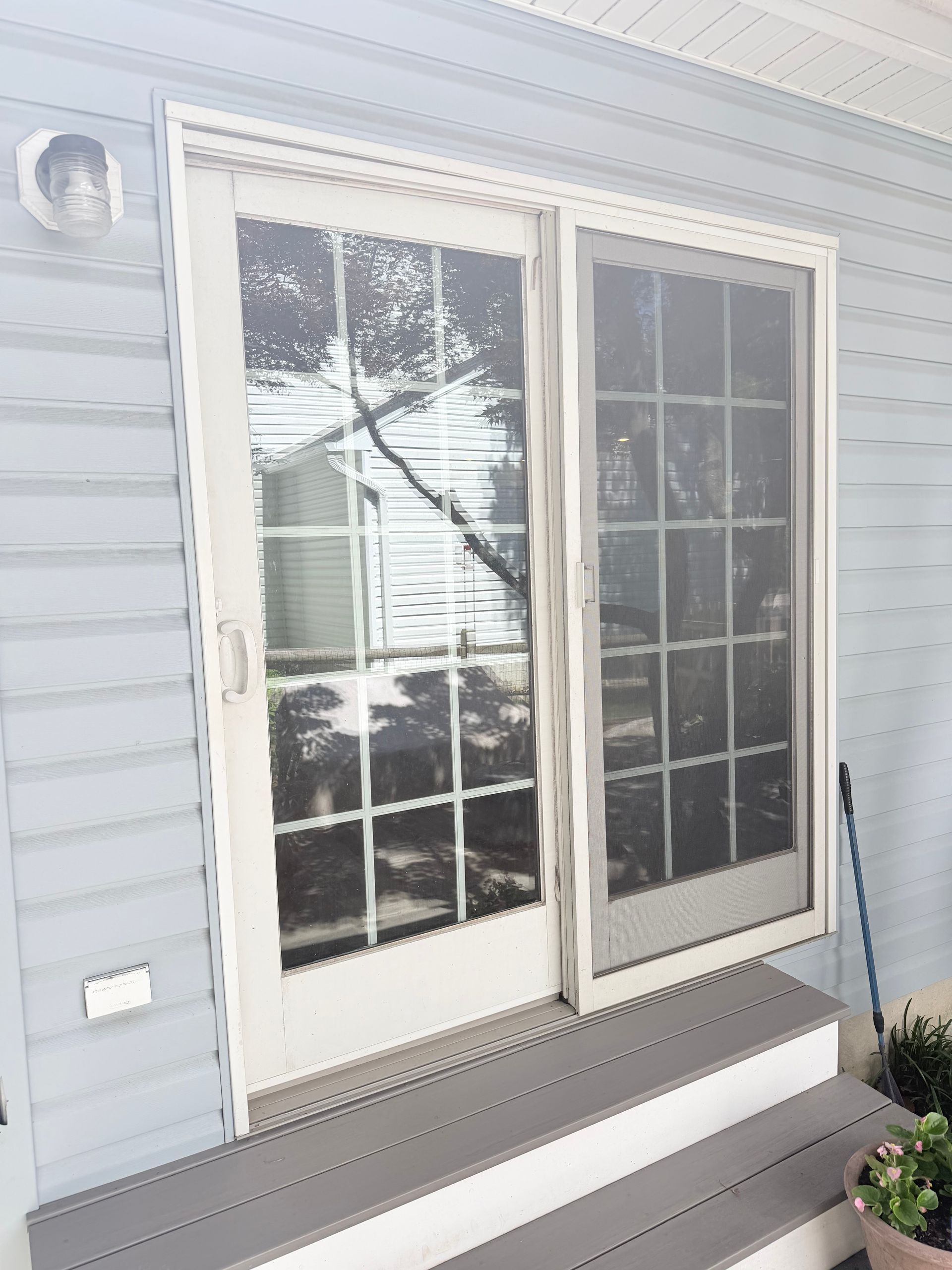 White French doors on a light blue house with gray steps and sun glare on the glass