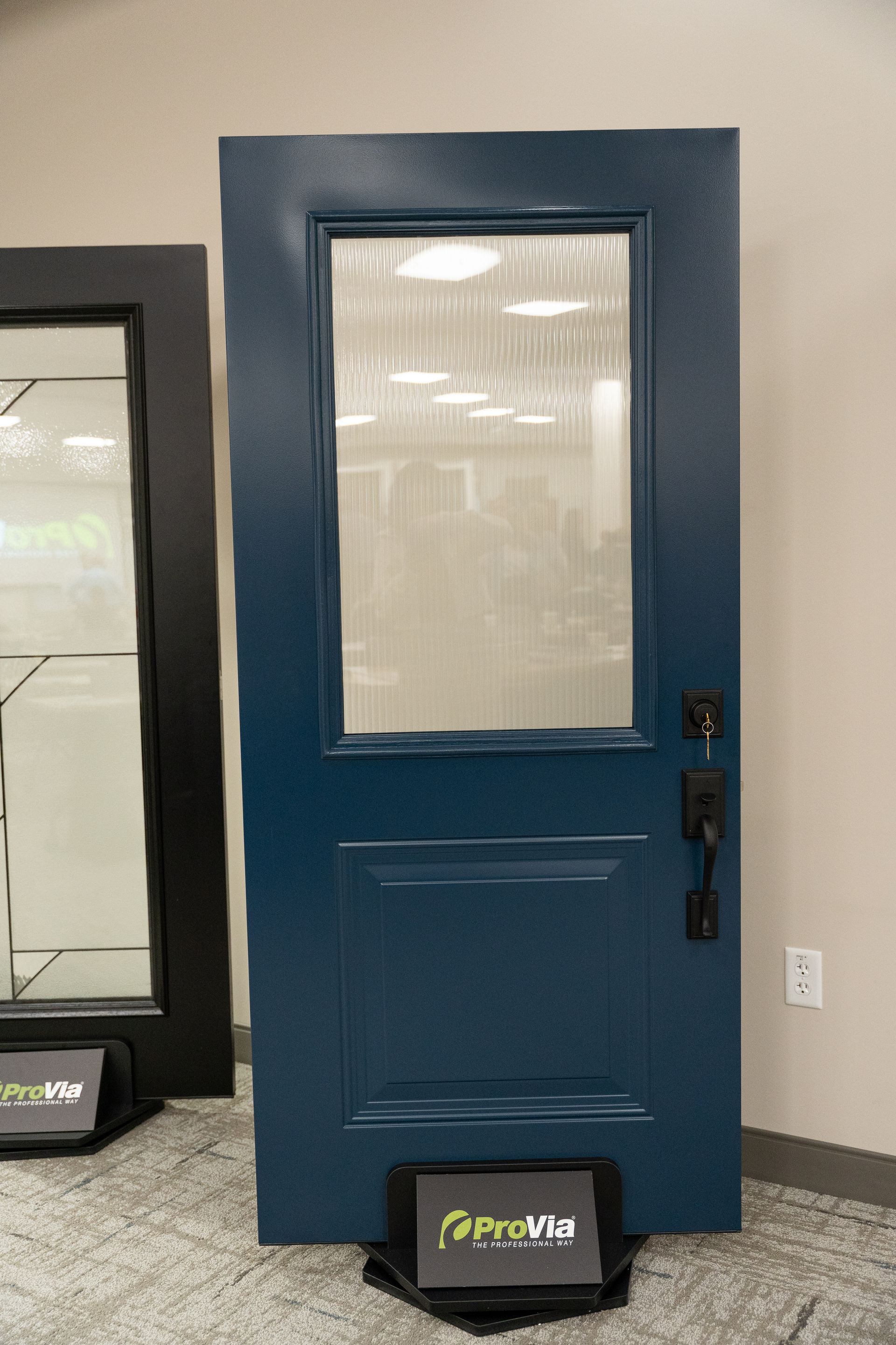 Blue door with frosted glass panel displayed indoors against a beige wall.