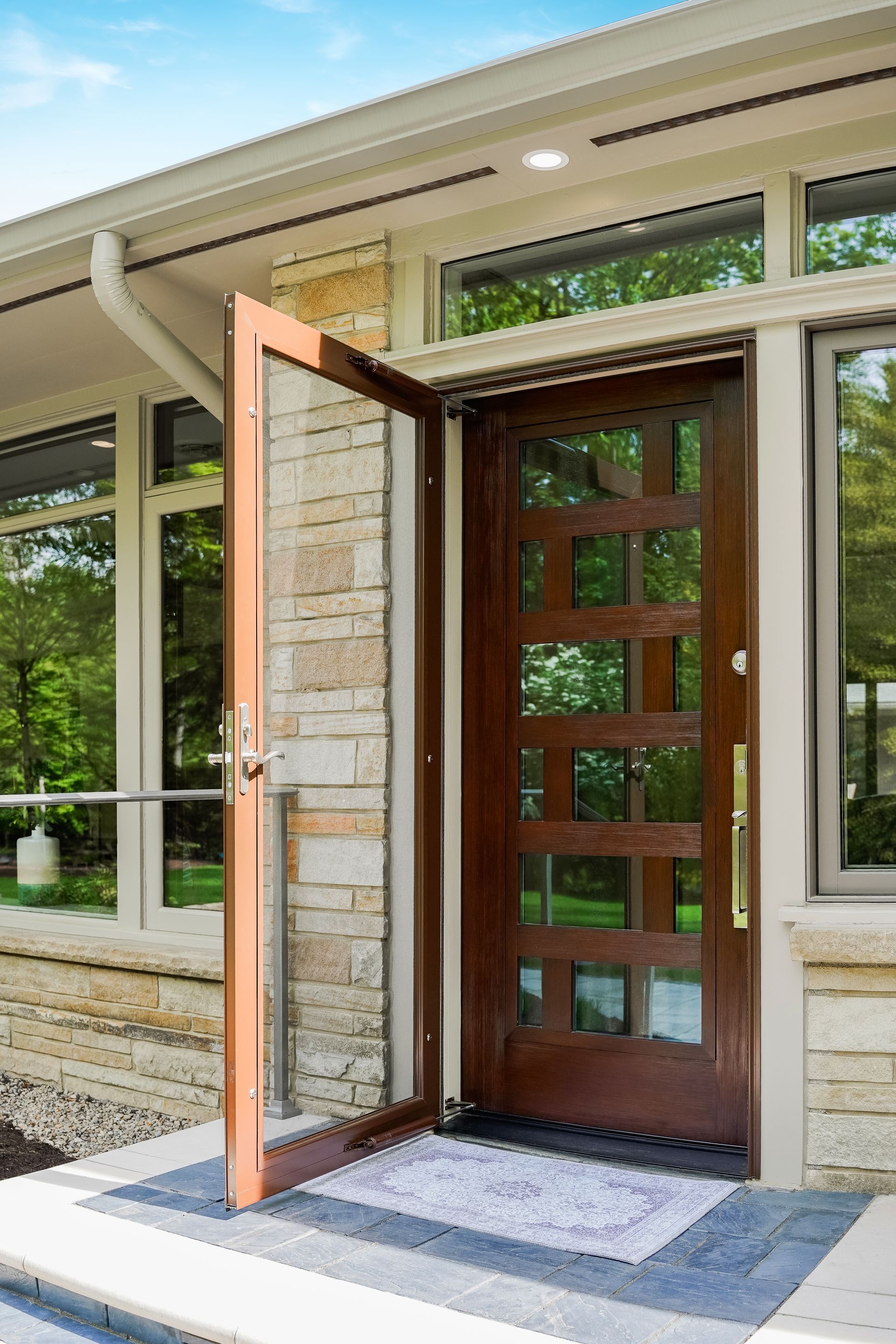 Open wooden front door with glass panels at a house entrance