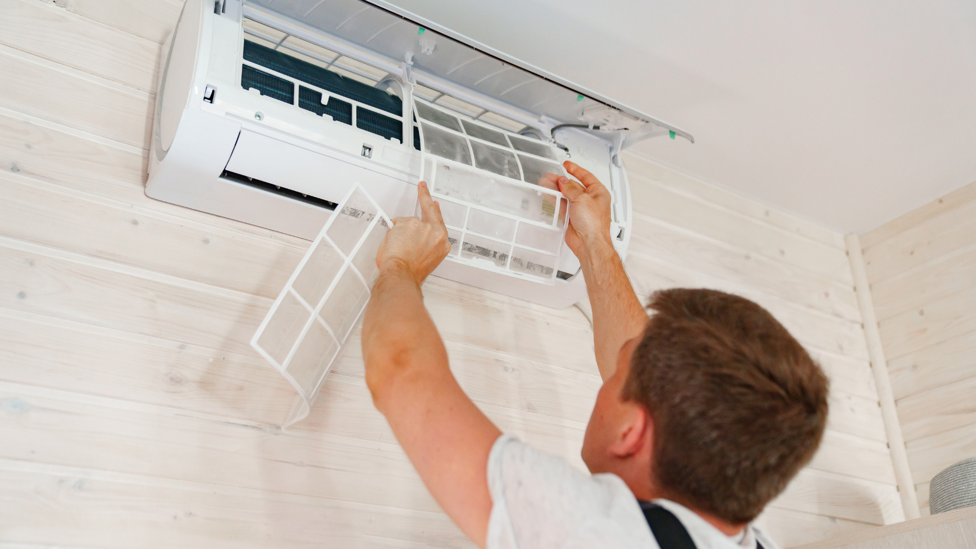 A man is cleaning the filter of an air conditioner.