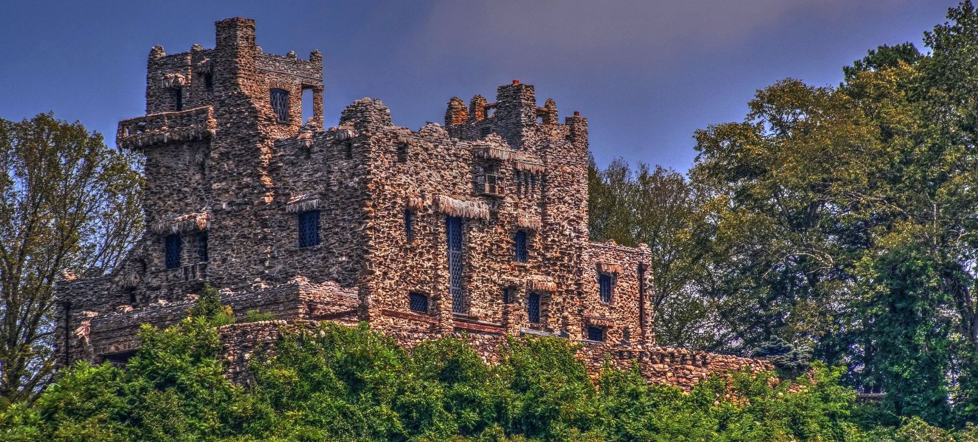 A medieval style castle surrounded by trees and bushes.