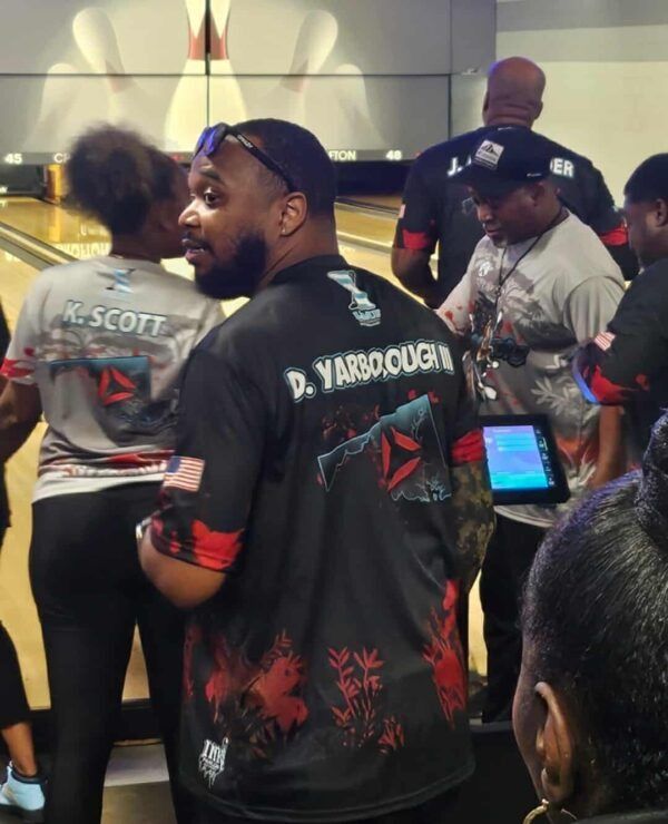 Crowded indoor event with people in black jerseys, including one with “D. Yarbrough” on the back.