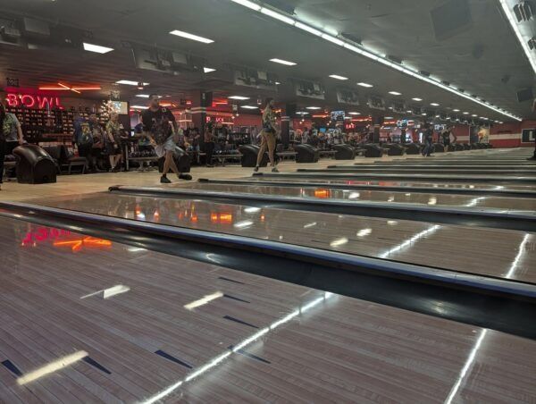 Bowling alley with lanes, overhead lights, and people bowling in the background
