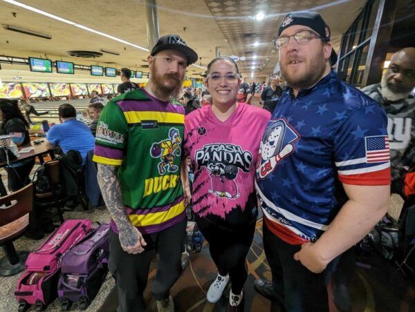 Three fans posing at a bowling alley in Ducks, Pink, and USA hockey jerseys