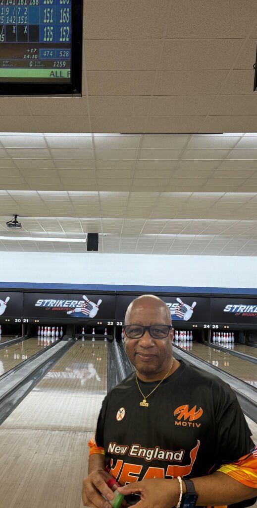 Bowling alley with a man in a black-and-orange shirt standing near the lanes