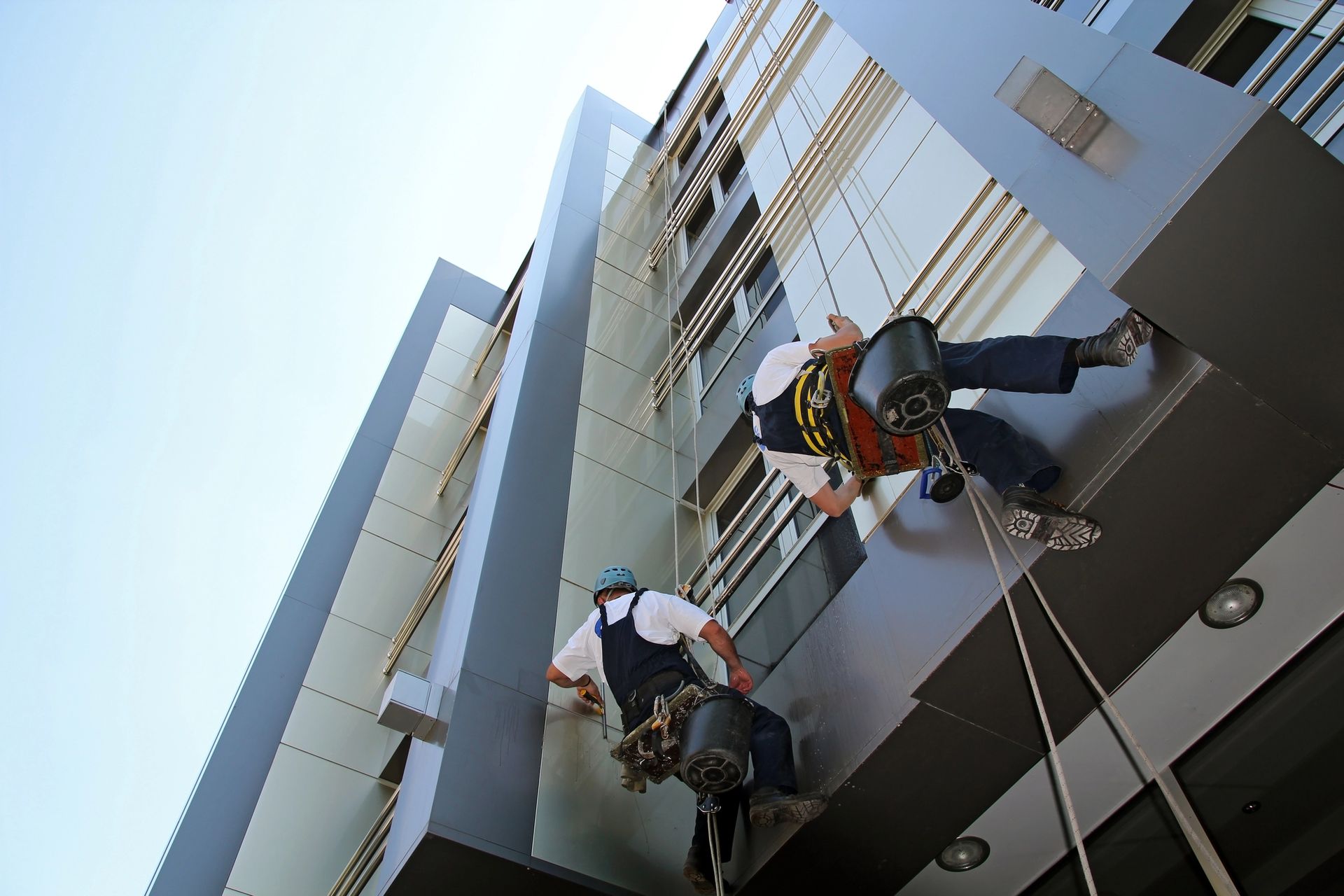 Dos hombres están subiendo por el costado de un edificio.