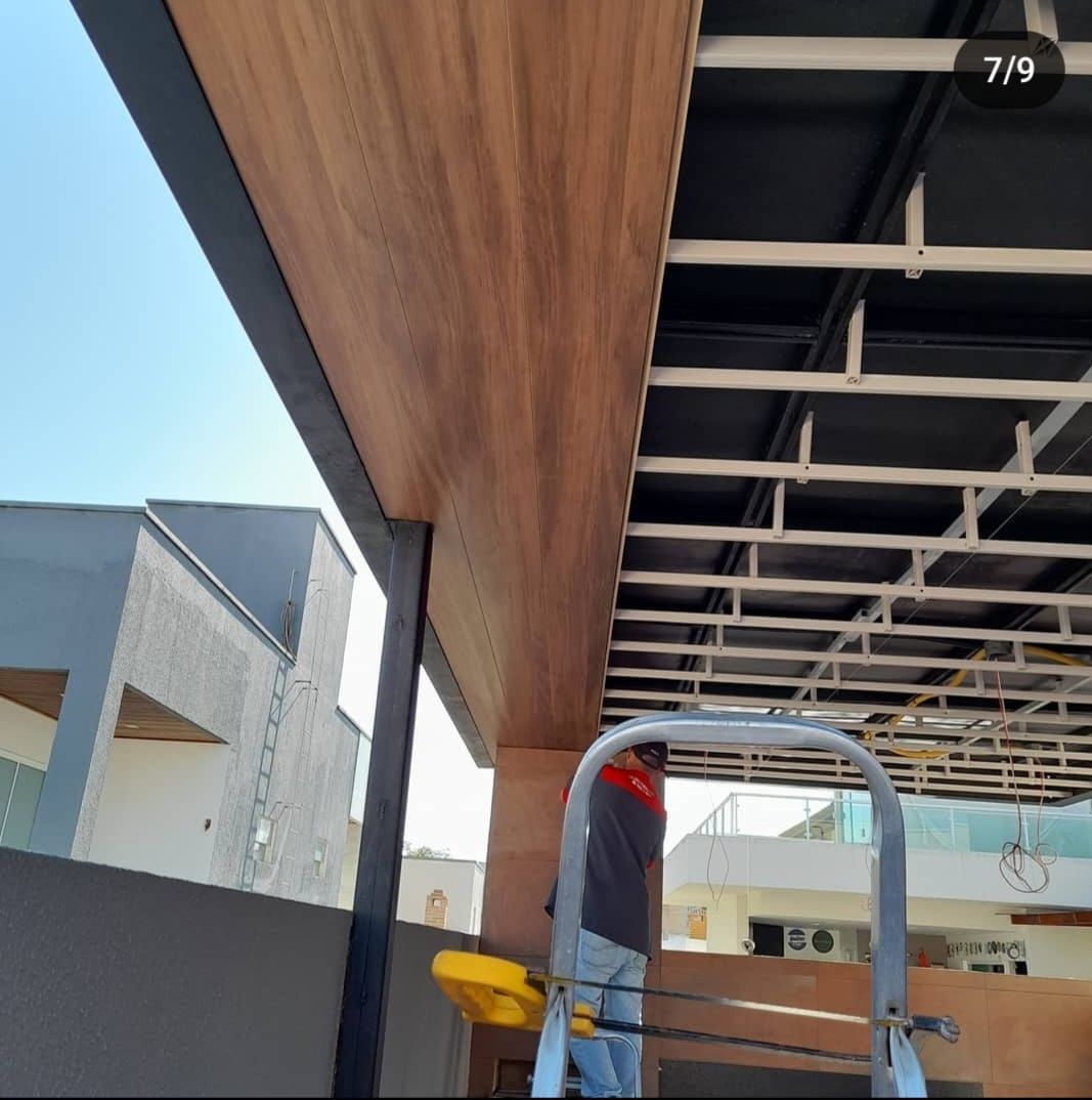 Un hombre en una escalera está trabajando en un techo.