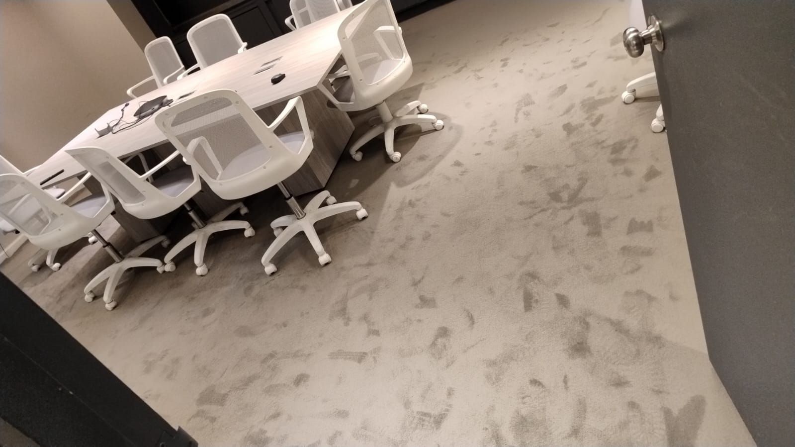 Una sala de conferencias con una mesa redonda y sillas blancas.