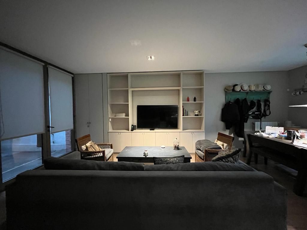 Una sala de estar con sofá, sillas, mesa y televisión.