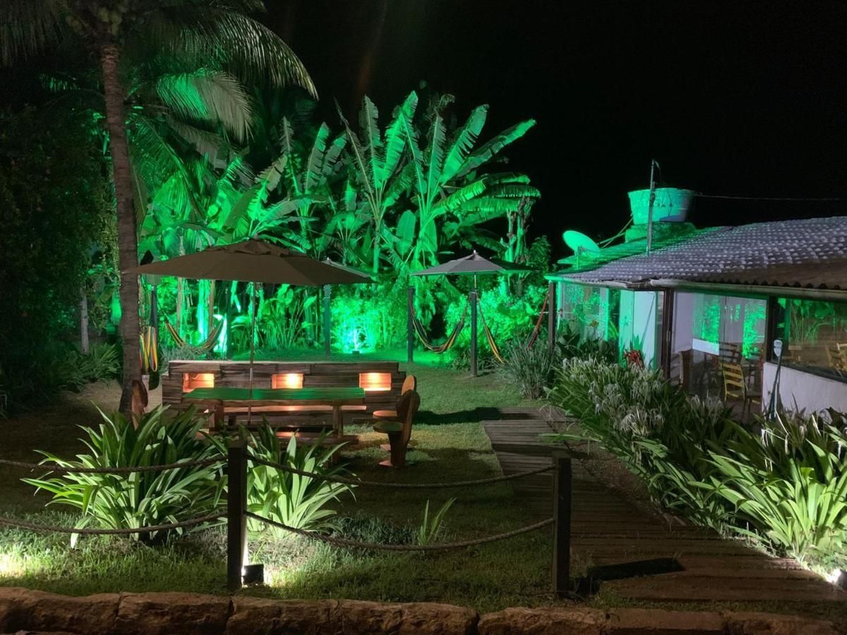 Um jardim verdejante com uma mesa de piquenique e guarda-sóis à noite.
