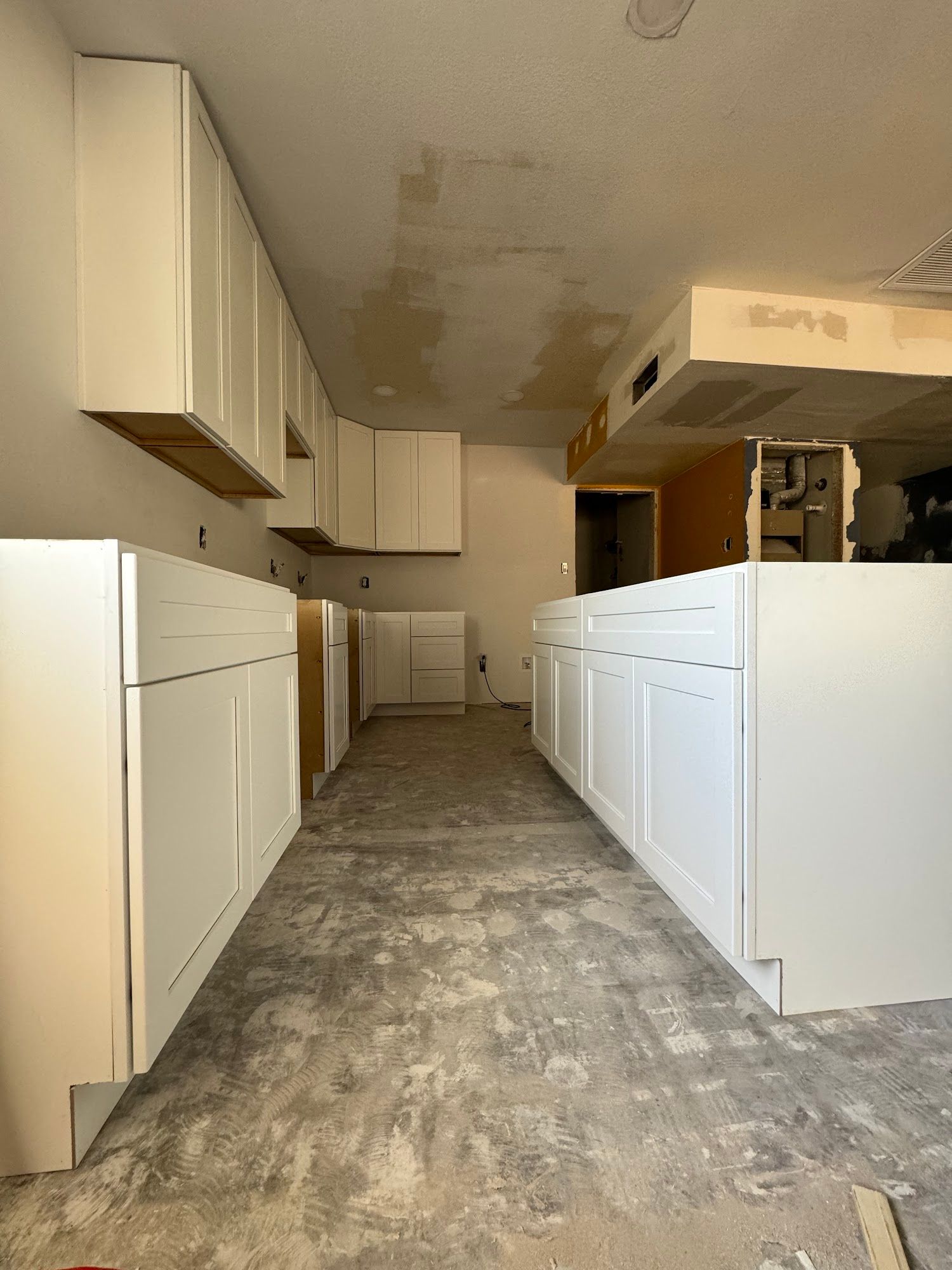 White kitchen with island, cabinets, stainless steel appliances, and dark hardwood floors.