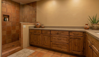 Dark gray kitchen cabinets installed on a wood floor, with a blank wall space for appliances.