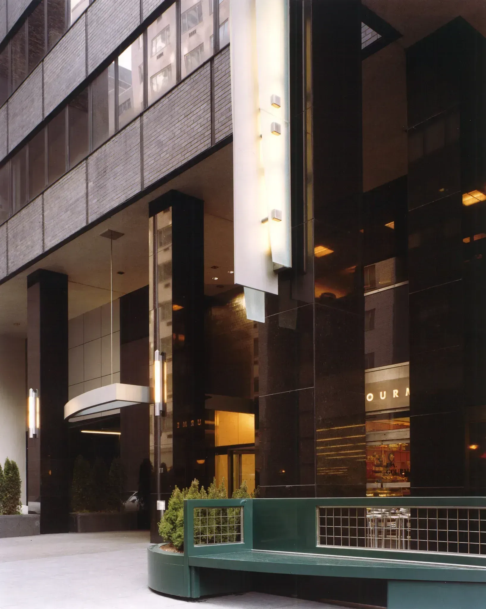 Building entrance with black pillars, recessed entry, and bench.