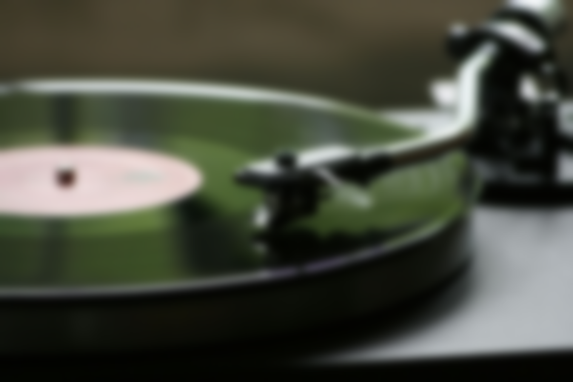 Turntable playing a record; close-up of the tone arm and black vinyl.