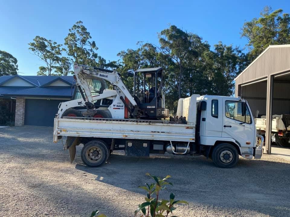 A Bobcat Excavator is Driving Down a Dirt Road — Jaya Rose Earthworks and Landscape Contractors In Gulmarrad, NSW