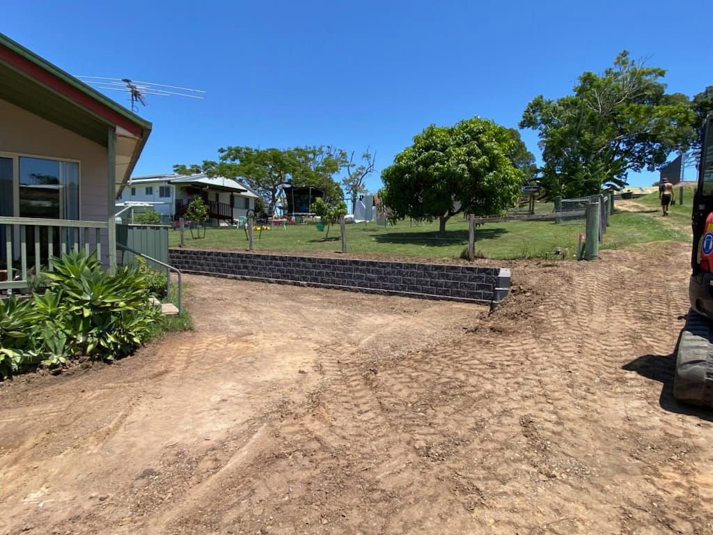A Tractor is Driving Down a Dirt Road in Front of a House — Jaya Rose Earthworks and Landscape Contractors In Gulmarrad, NSW