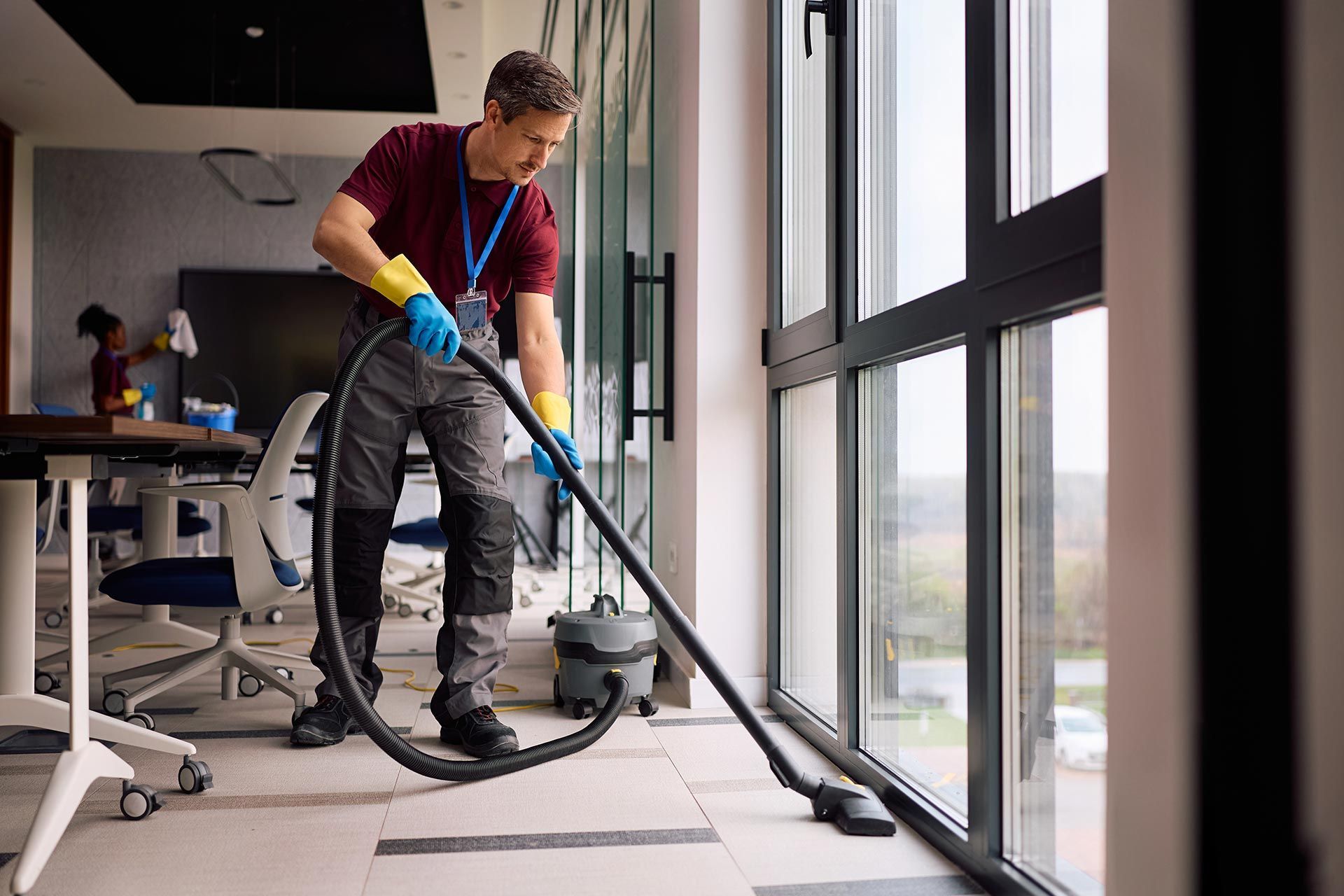 Professional cleaner vacuuming floors in modern office building.