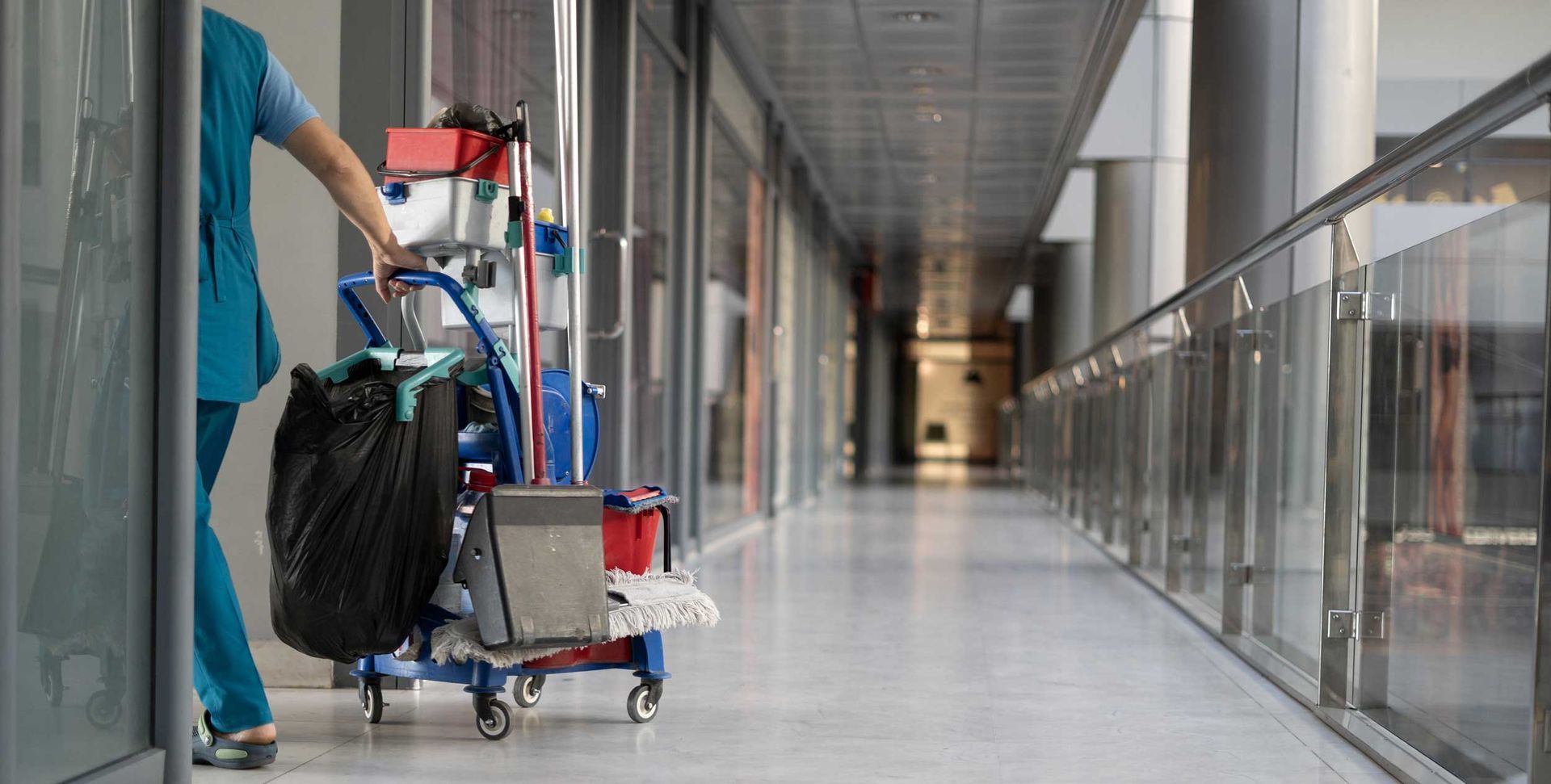 An employee pulls a trolley for cleaning offices. An employee pulls a trolley for cleaning offices.