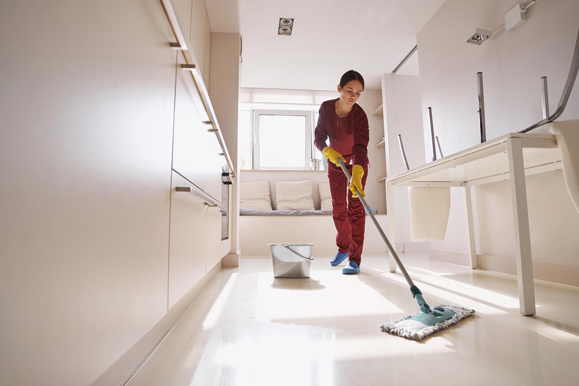 Concentrated uniformed professional janitor doing wet cleaning.