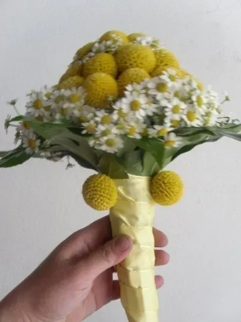Bouquet di fiori gialli e margherite bianche, avvolti in carta giallo pallido.
