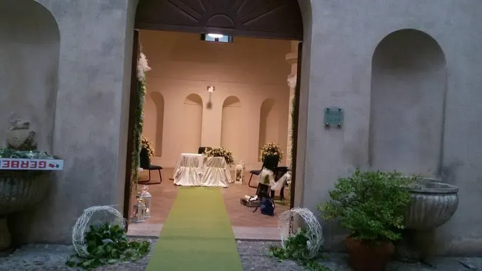 L'ingresso del cortile, con un tappeto verde, conduce a un tavolo nuziale decorato all'interno di un arco in pietra.