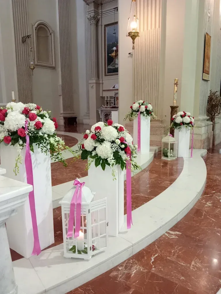 Naglia nuziale bianca con composizioni floreali rosa e rosse e lanterne accanto a scalini curvi