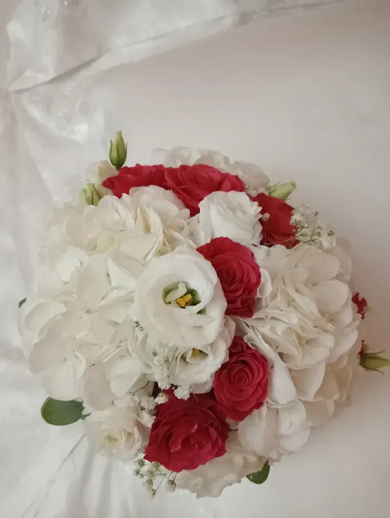 Bouquet di fiori bianchi e rossi su uno sfondo di tessuto chiaro.