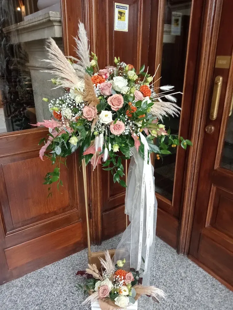 Composizioni floreali con nastro bianco all'ingresso in legno di una chiesa.