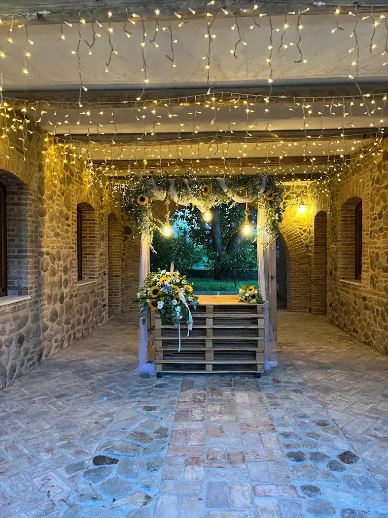 Cortile in pietra coperto con luci decorative, un piccolo altare in legno e piante al centro.