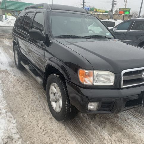 A black suv is parked in the snow in front of a building.
