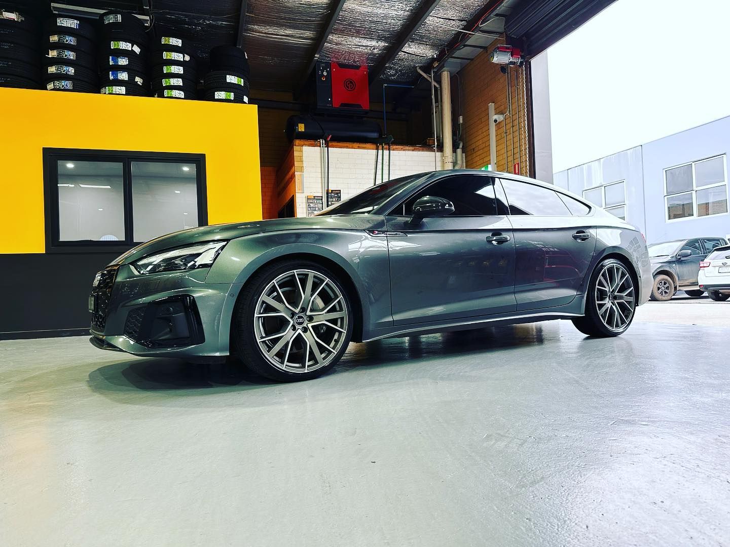 Gray Audi RS5 coupe with custom wheels in a garage setting.
