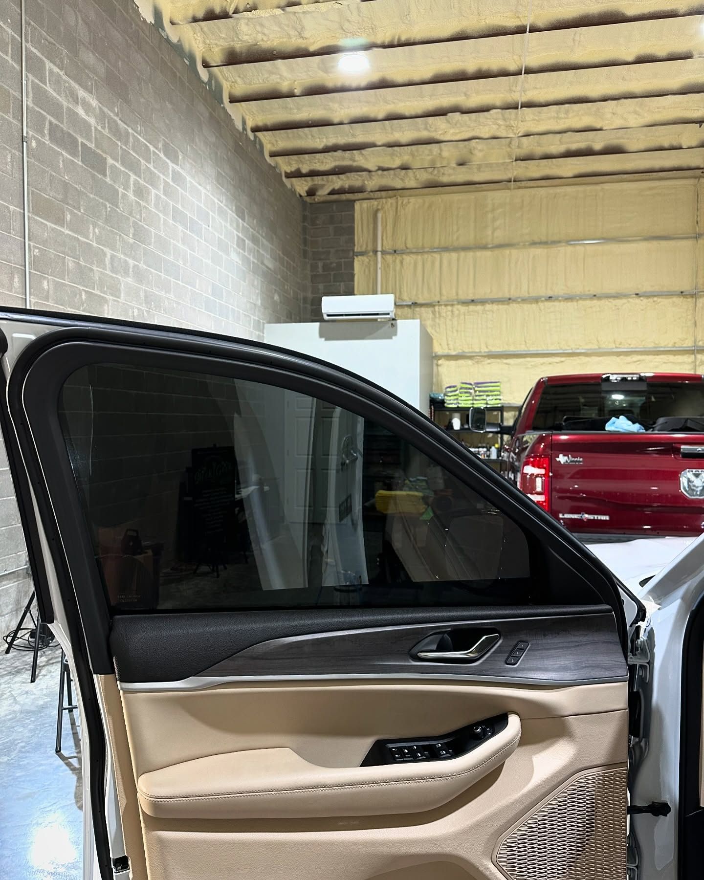 A white car is parked in a garage with its door open.