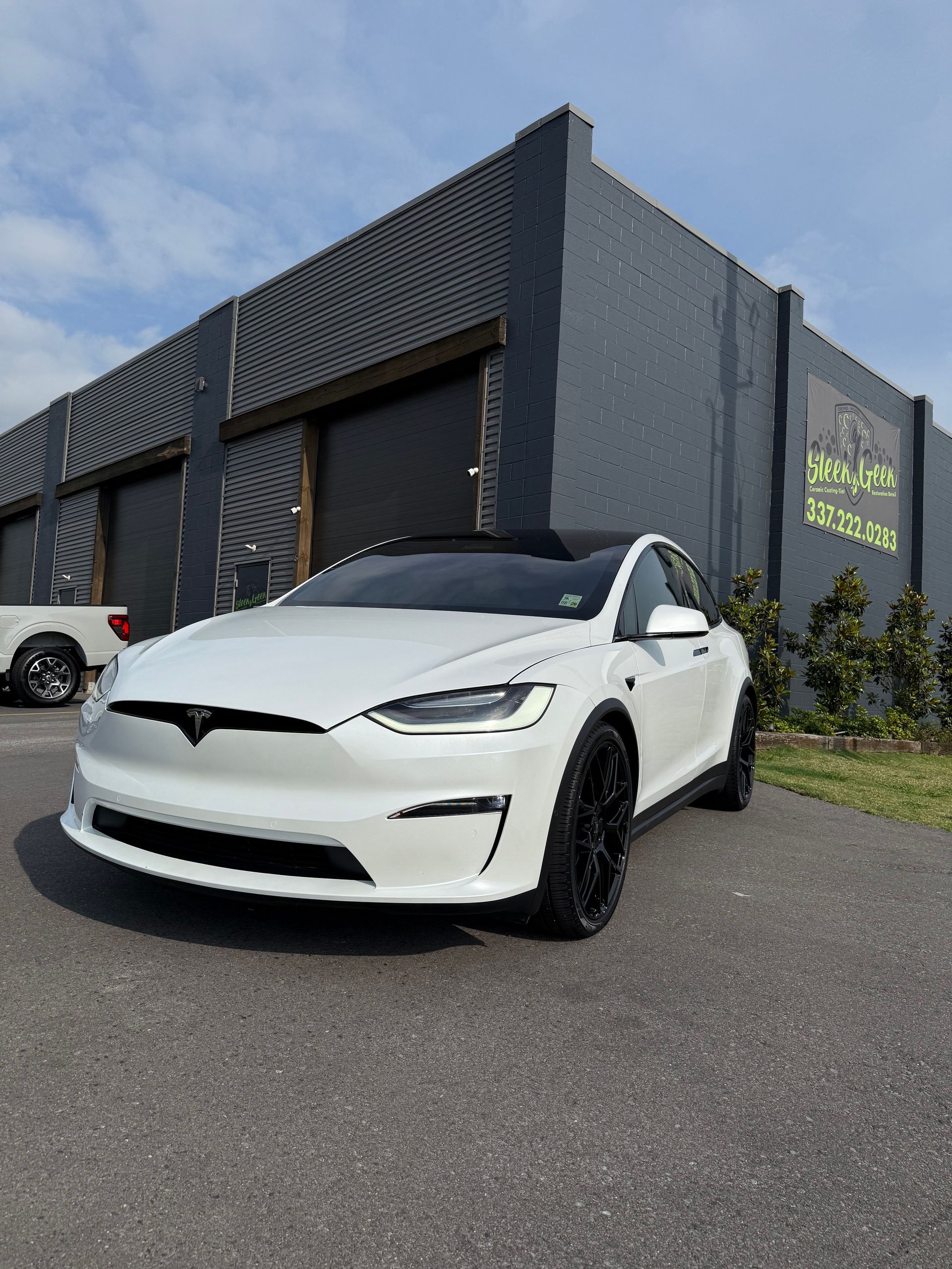 A white tesla model x is parked in front of a building.