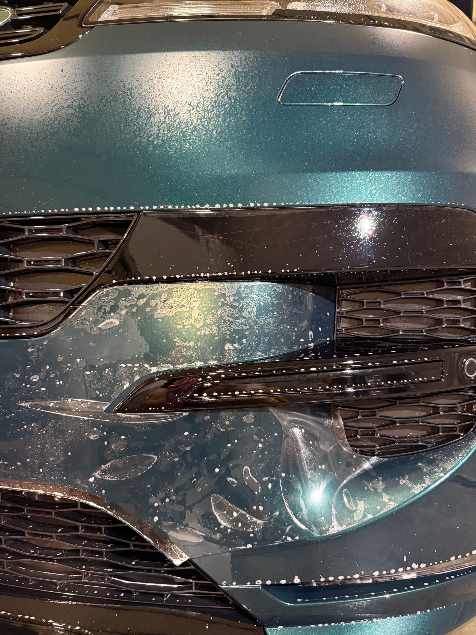 A close up of a car 's front bumper wrapped in plastic.