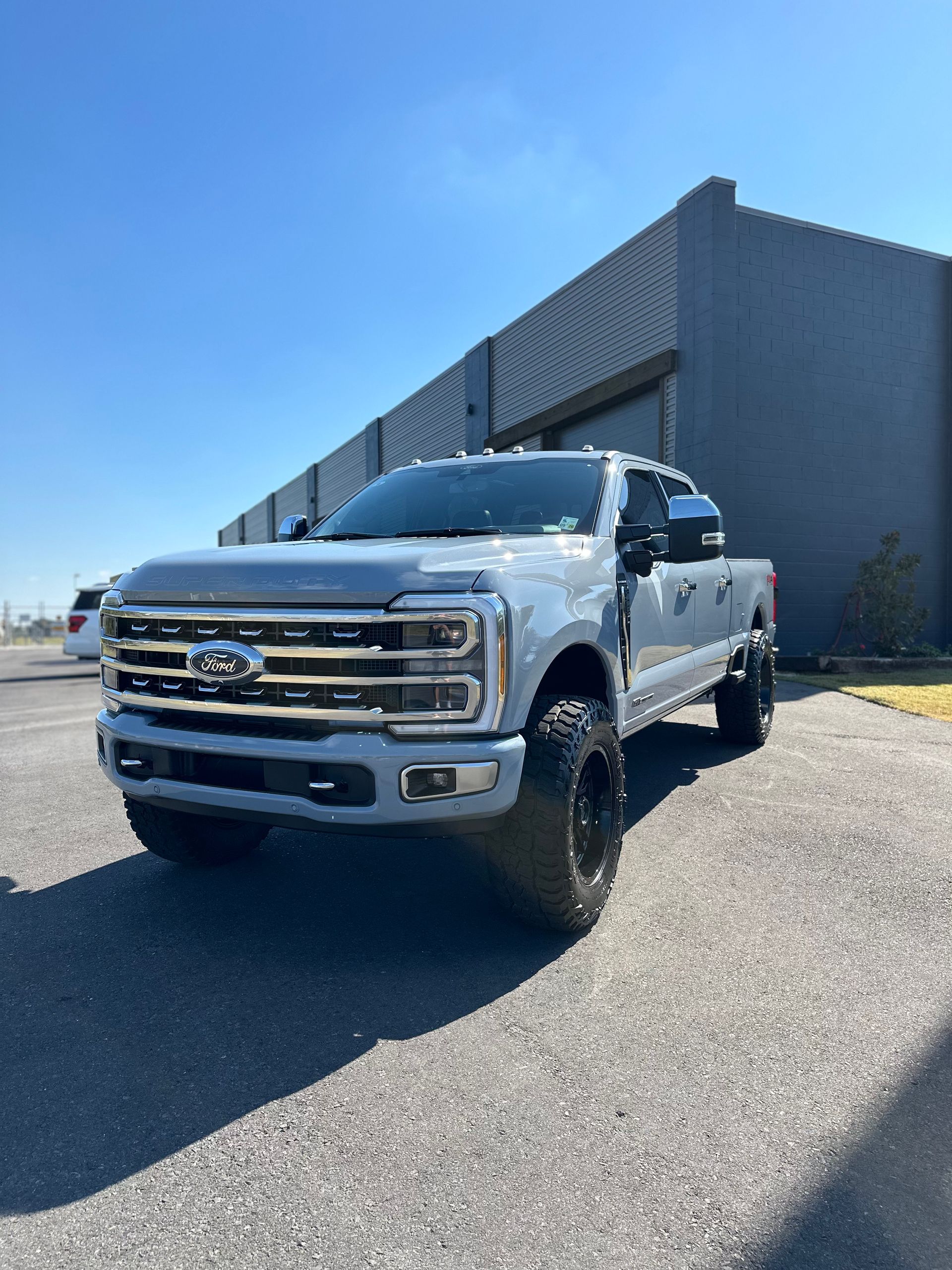 A silver ford truck is parked in front of a building.