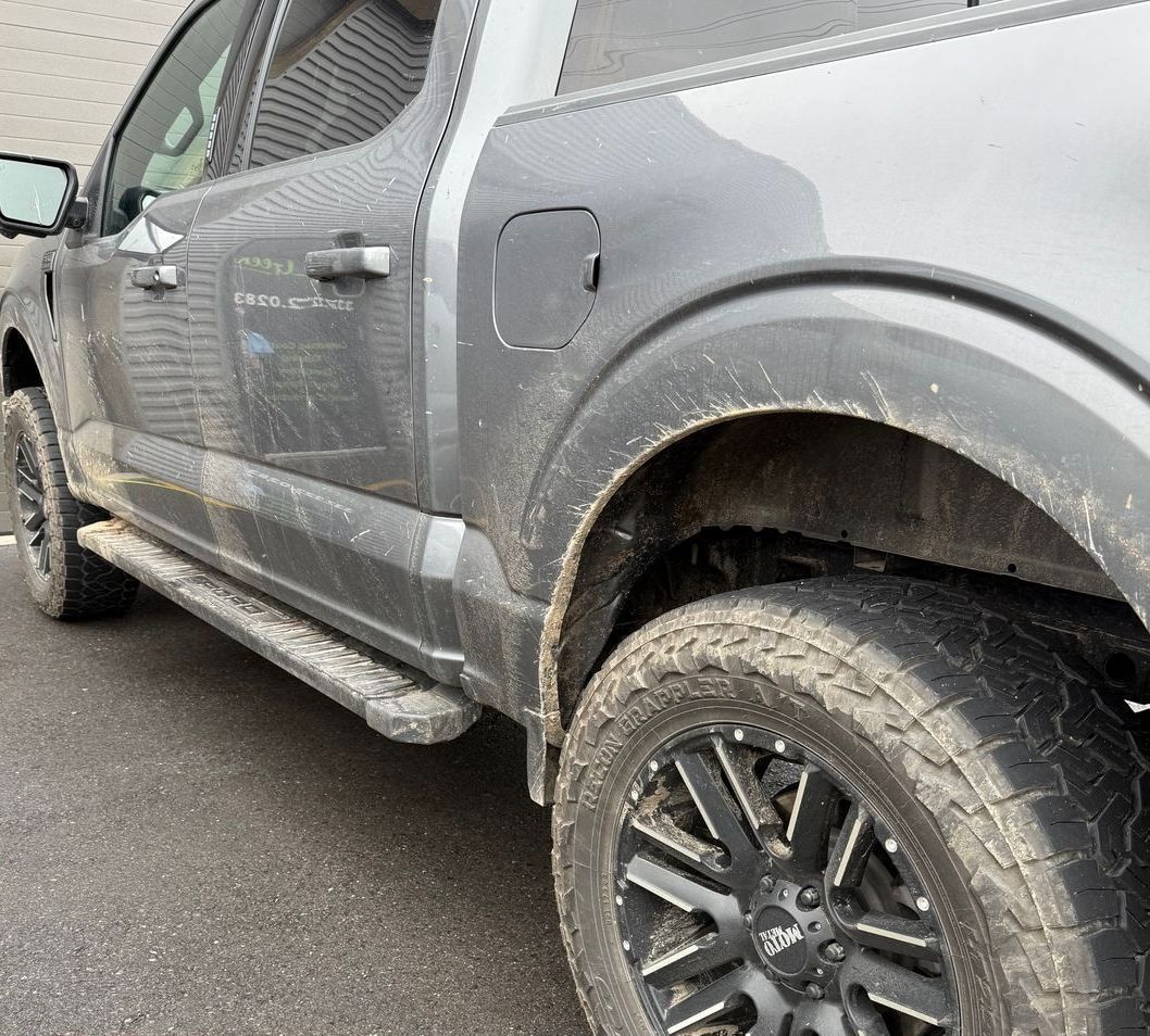 A dirty truck is parked on the side of the road.