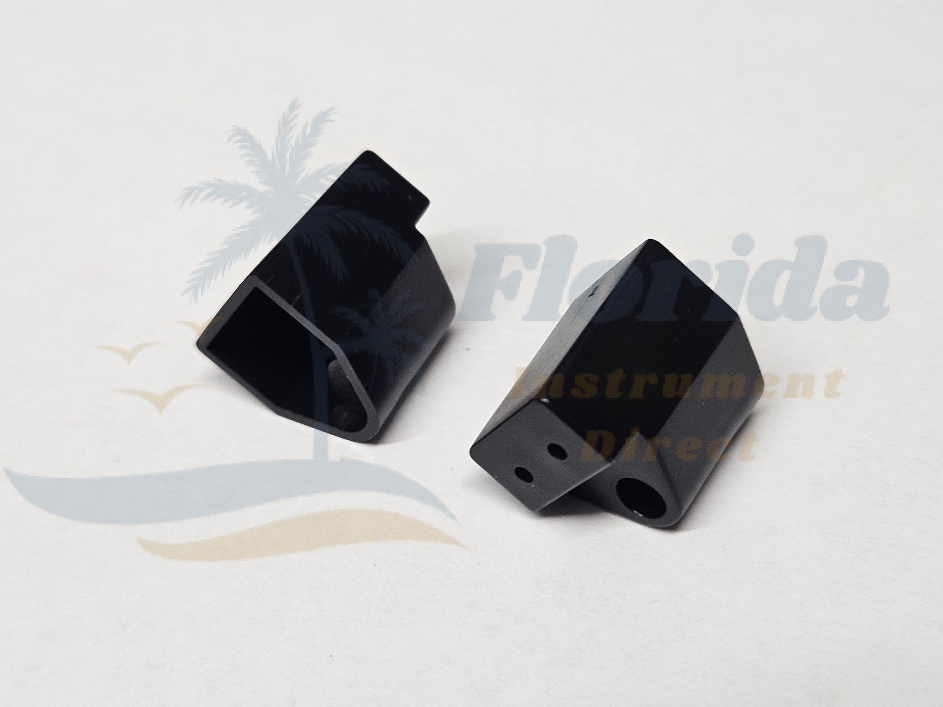 Two black plastic mechanical parts on a light background