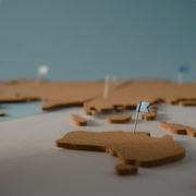 Miniature map with a small flag marker on a brown land mass, in shallow focus