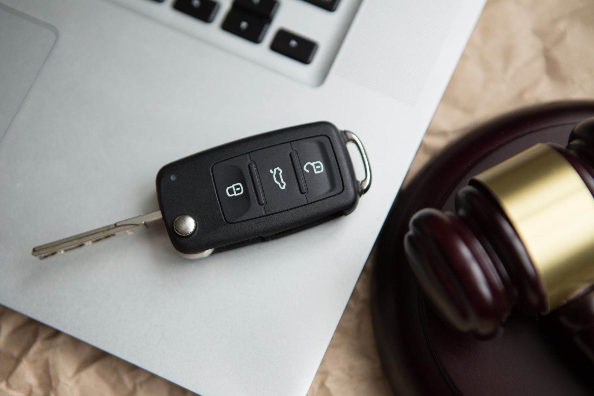 Car key and gavel on a laptop, implying a legal or auction context.