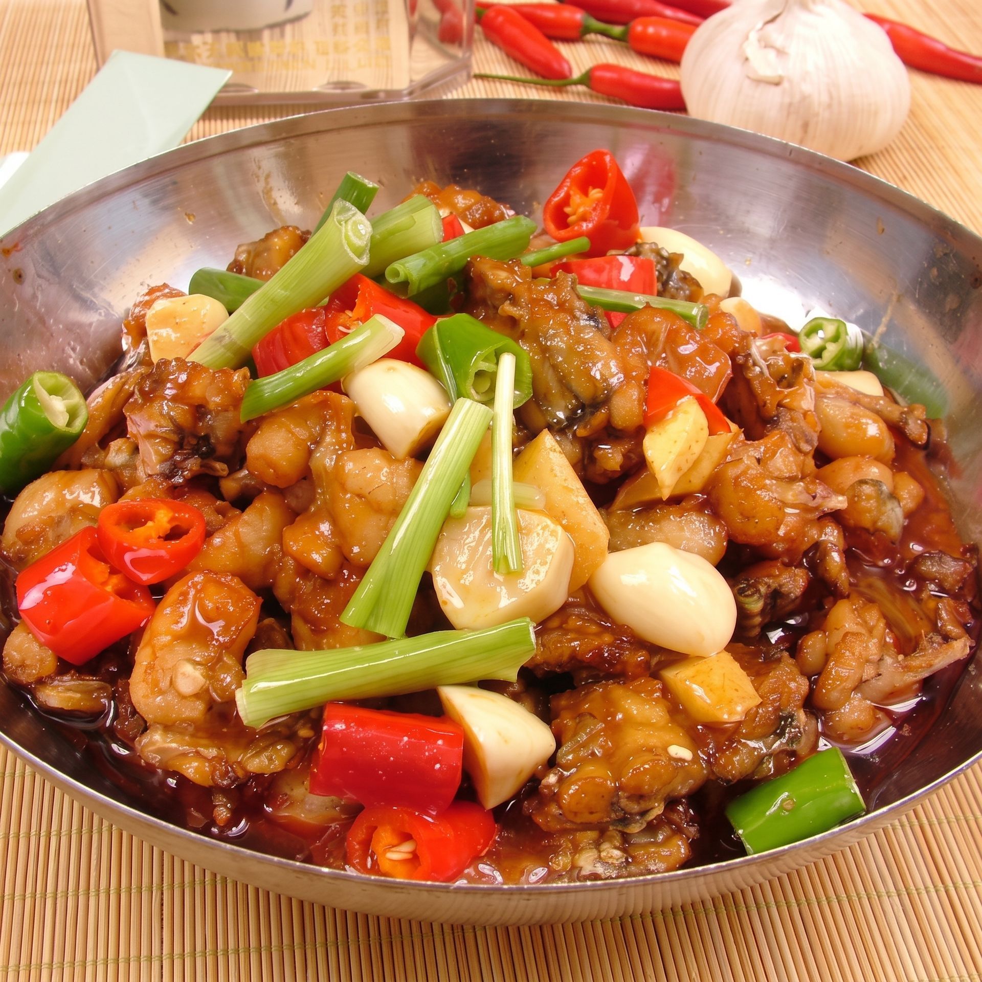 Bowl of saucy stir-fried noodles topped with garlic, green onions, and red chilies
