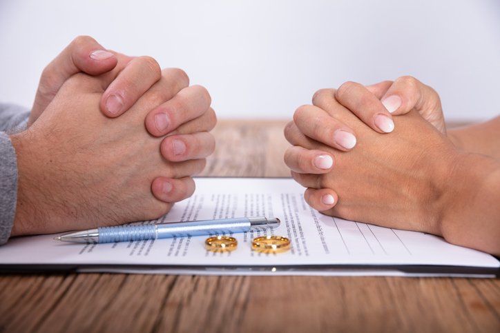 Divorce agreement — Elkhart Lake, WI — Pro Se Divorce & Mediation Services S.C. Hands clasped over a divorce agreement, rings on document, symbolizing a split.