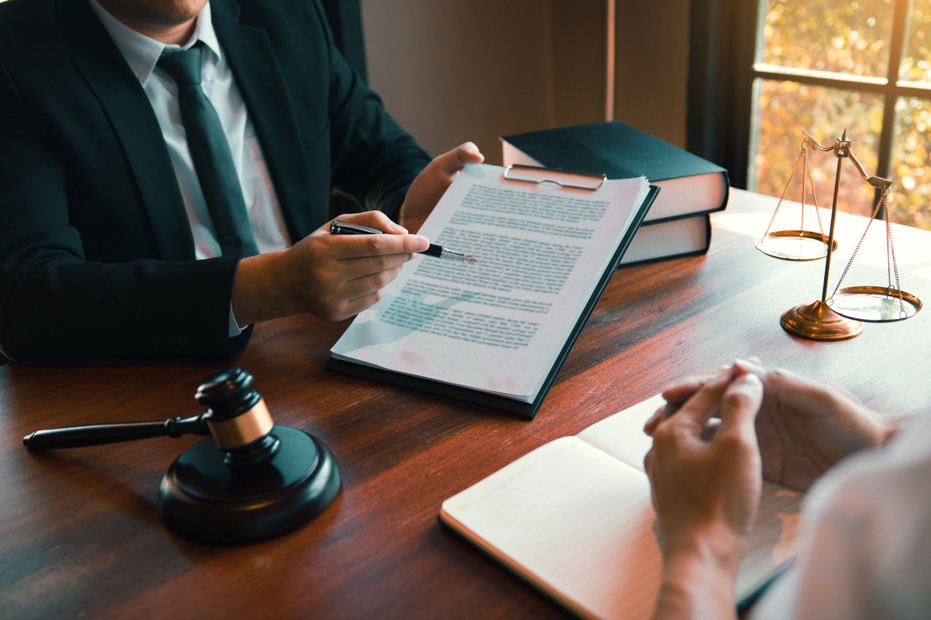 Legal proceedings and legal advice — Elkhart Lake, WI — Pro Se Divorce & Mediation Services S.C. Lawyer pointing at document for a client; scales of justice and gavel on the table.