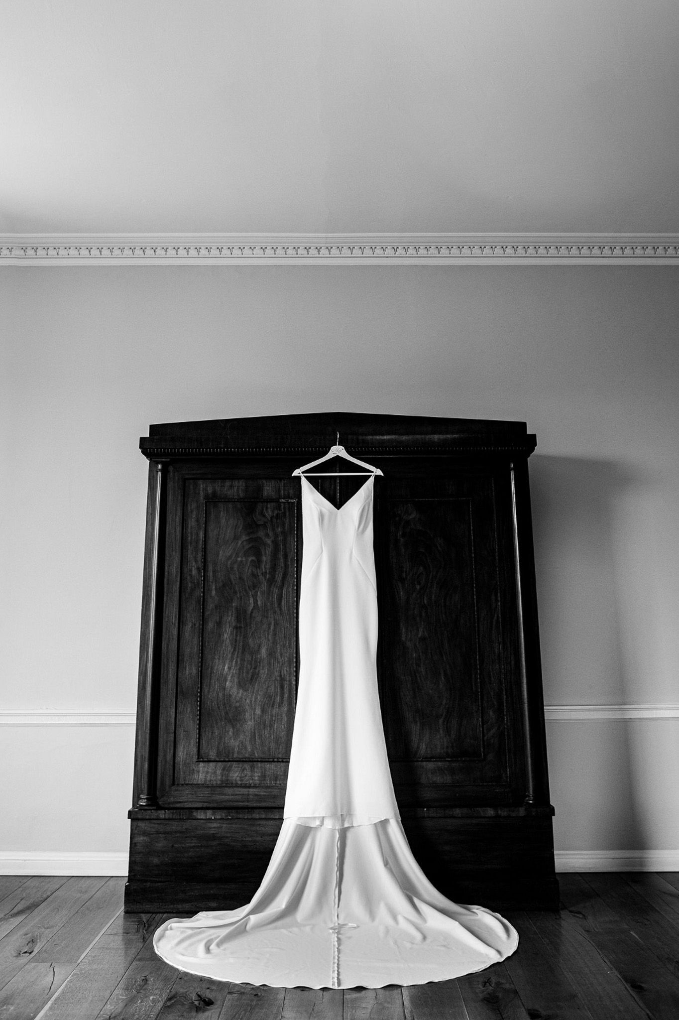 a black and white photo of a wedding dress hanging on a hanger .