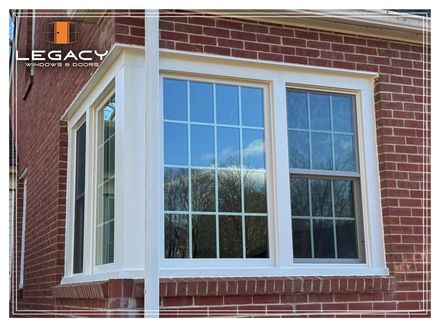 Bay window with white trim in a brick building; reflections in the glass.